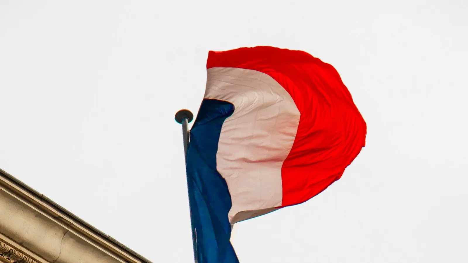 The French flag flying above the cornice of an official building