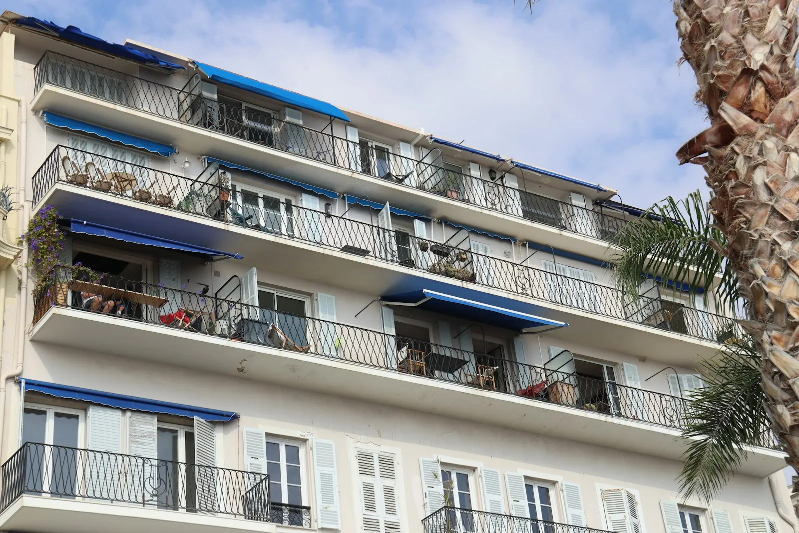 An apartment building facade in Nice with wrought-iron balconies and blue awnings